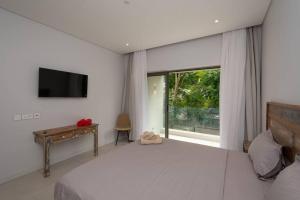 Un dormitorio con una cama y un televisor y una ventana. en Luxueux Appartement 3 Chambres situé à La Pointe, en Grand Baie