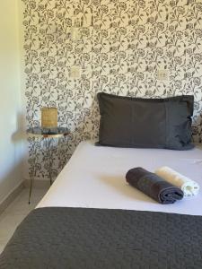 a bed with a black pillow and a wall at Skopelos Inn in Stafylos