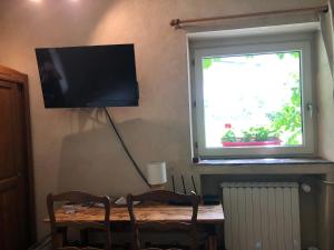 un televisor en una pared junto a una mesa con una ventana en Domaine Moulin de Boiscorde, en Rémalard