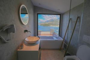 希马拉Anassa Suites的带浴缸和盥洗盆的浴室以及大窗户。