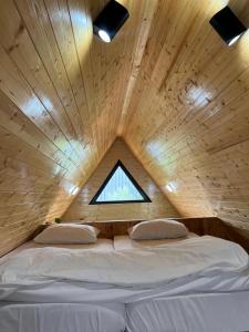 Bett in einem Holzzimmer mit Fenster in der Unterkunft Karaağaç Bungalov & Tiny House in Hatay