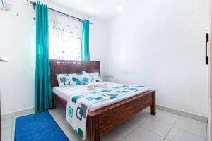 Ce lit se trouve dans un dortoir doté d'une fenêtre avec des rideaux verts. dans l'établissement Bstan Homes 3 Bedroom Mombasa With AC, à Mombasa 16 autres photos