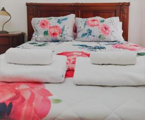 Una cama con almohadas blancas y flores rosas. en Julia House Holidays Nazaré, en Nazaré