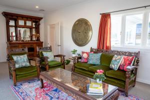 a living room with a green couch and chairs at Grace Road Cottage in Tauranga