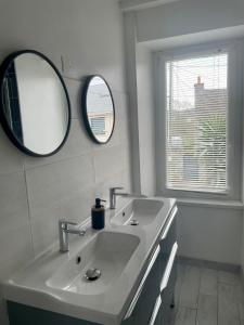 a white bathroom with two sinks and a mirror at Maison de vacances 5 voyageurs in Cherbourg en Cotentin +31 photos