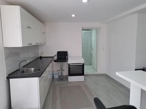 a white kitchen with a sink and a stove at Apartman Avlija in Tuzla