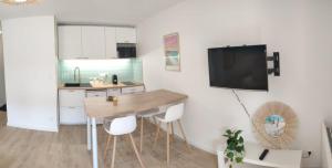 a kitchen with a table and a tv on a wall at Charmant appartement T2 - Proposition de séjours avec des activités locales - 200m de la plage avec jardin et terrasse- RDC in Carnac +10 photos