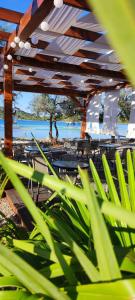 a wooden pergola with tables and chairs and a body of water at Mobile homes King, Camp Dida in Pirovac