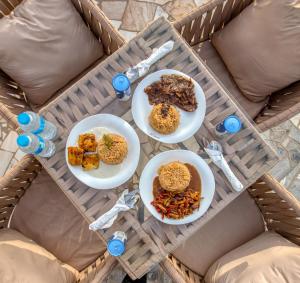 una mesa con tres platos de comida. en Villa Khufu Pyramids Inn, en El Cairo