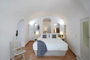 a bedroom with a white bed and a chair at Elegant Santorini House Villa Horizon Caldera View-Outdoor Hot Tub Oia in Thólos