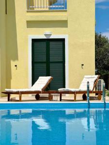 twee ligstoelen naast een zwembad bij Maison Rivière in Lefkada