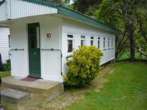 a small white building with a green door at Alexanders Holiday Park in Picton