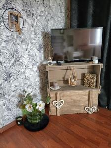 uma sala de estar com televisão e um vaso de flores em Les Bichettes em Mortagne-sur-Sèvre