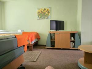 a room with a tv on a stand with a bed at Hotel Promenade in Palanga