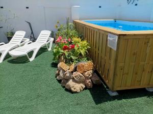 a wooden hot tub with white chairs and flowers at Casa Jienense 