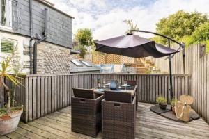 a patio with an umbrella on a wooden deck at Dukes House - first floor apartment in Padstow