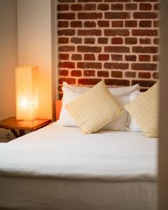 a bed with two pillows and a brick wall at Laxmi Niwas in Pātan