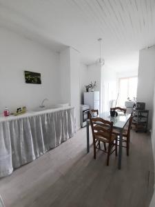 Ein weißes Zimmer mit einem Tisch und Stühlen. in der Unterkunft L'oasis in Mouleydier