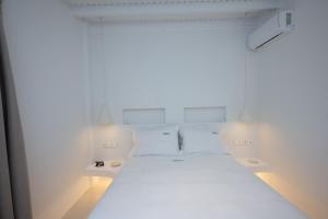 Habitación blanca con 1 cama y 2 mesas en Cavo Blue Villas, en Playa de Elia