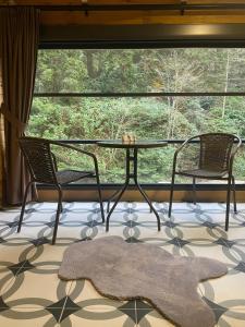 einen Glastisch und zwei Stühle vor einem Fenster in der Unterkunft Ayder Villa Gencal King in Ayder Yaylasi