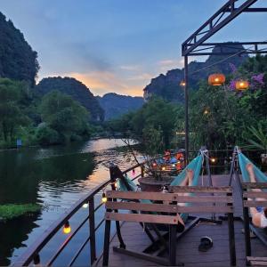 HoangLong Riverside Homestay في نينه بينه: مقعد جالس على مرسى بجانب نهر
