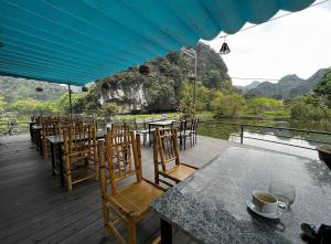una terraza con mesas y sillas y vistas al río en HoangLong Riverside Homestay, en Ninh Binh