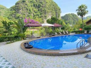 uma piscina num resort com cadeiras e guarda-sóis em HoangLong Riverside Homestay em Ninh Binh