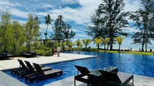 a swimming pool with chairs and a person walking by it at SS Staycation @Roxy Sematan Beach Apt in Sematan