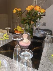 una mesa con dos copas de vino y un jarrón con flores en Jolie maison de village en Capendu