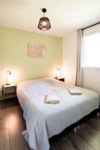 une chambre avec un grand lit avec deux serviettes dessus dans l'établissement Appartement cosy 5 mins Honfleur piscine terrasse, à Équemauville