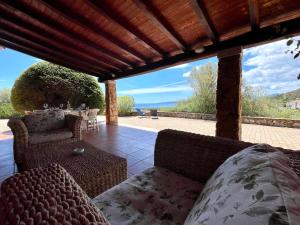 un patio con divano e sedie. di VILLA Lu FRAILI IMMERSA NELLA NATURA VISTA MARE a Nuragheddu
