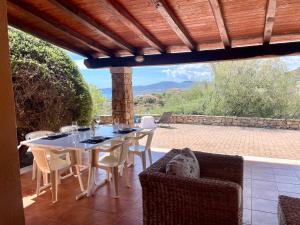 un tavolo da pranzo e sedie su un patio di VILLA Lu FRAILI IMMERSA NELLA NATURA VISTA MARE a Nuragheddu