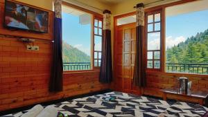a bedroom with windows with a view of the mountains at Kavyansh Forest Valley in Dalhousie