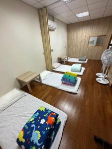 a room with three beds and a fan at 枋寮枋居背包客棧Fang Ju Backpackers in Fangliao