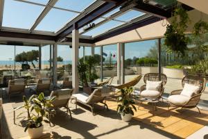 a patio with chairs and tables and windows at Savoy Beach Hotel & Thermal Spa in Bibione