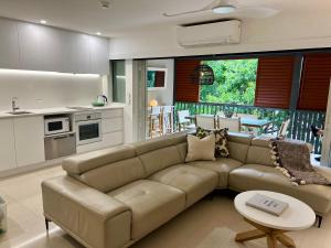 a living room with a brown couch and a kitchen at Noosa Beach Apartment on HASTING ST French quarter resort.Noosa Heads in Noosa Heads