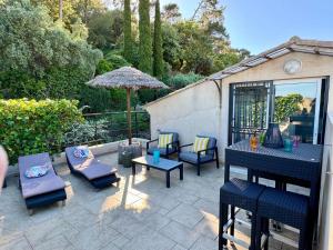 un patio con sedie, tavoli e un ombrellone di Nid douillet vue mer Hyères a Hyères