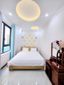a white bedroom with a bed and a mirror at Apec Sunsea Condotel Phu Yen in Liên Trì (3)