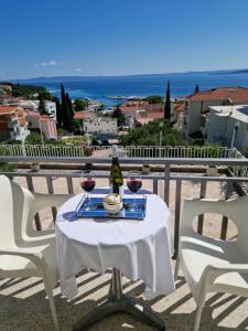 a table with two glasses of wine on a balcony at Apartments Šarić in Baška Voda