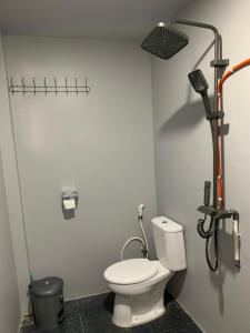 a bathroom with a white toilet and a shower at NASRUL HOUSE HOMESTAY FOR BACKPACKERS in Maros