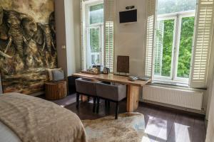 een slaapkamer met een bureau in een kamer met ramen bij Bouteaque Hotel in Maastricht