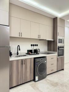 a kitchen with white cabinets and a washing machine at Khozama Living 2 - Alnahda in Jeddah