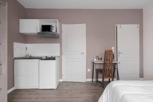 a kitchen with white cabinets and a bed and a table at Les Lilas in Podensac
