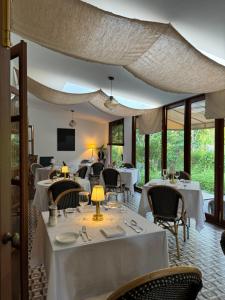 a restaurant with white tables and chairs and windows at Sela Chiangmai in Chiang Mai