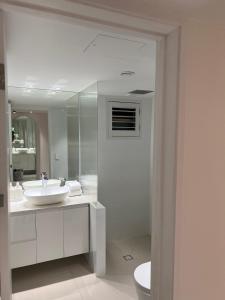 Baño blanco con lavabo y aseo en Noosa Beach Apartment on HASTING ST French quarter resort.Noosa Heads en Noosa Heads