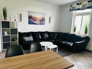 uma sala de estar com um sofá de couro preto e uma mesa em Kapitänshaus an der Warnow mit Sauna em Rostock