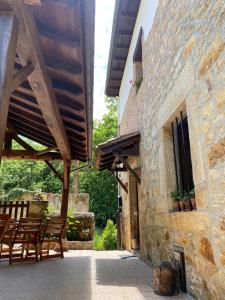 un patio con sillas de madera y un edificio de piedra en Apartamentos Rurales La Caviana, en Cangas de Onís