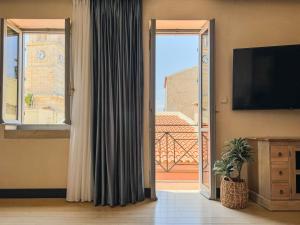 a room with a door open to a balcony with a television at Vranas Ambiance Hotel in Chania
