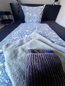 a bed with a blue and white comforter and two pairs ofippersomaly at Apartment No.9 in Husum