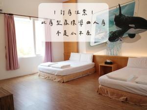 una camera con due letti in una stanza con scrittura a muro di Koppie Inn a Xiaoliuqiu